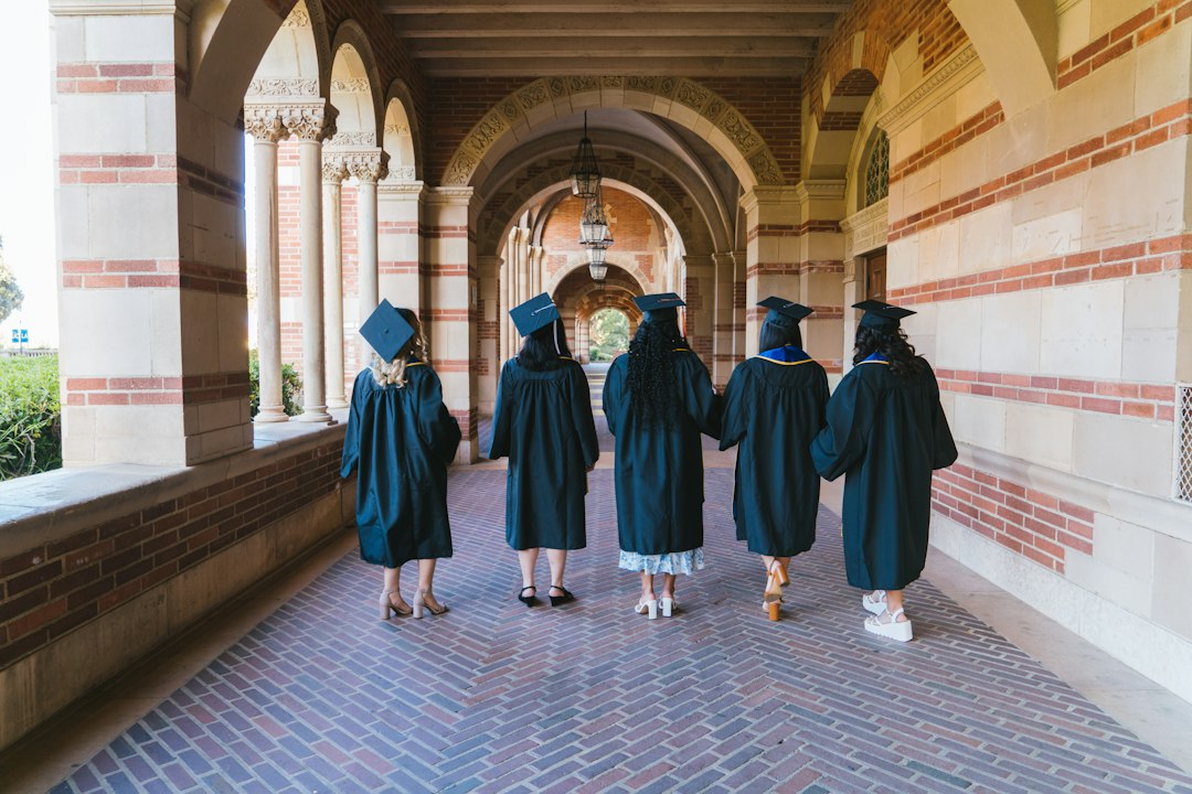 Absolvenți în robe mergând pe aleea unui campus universitar